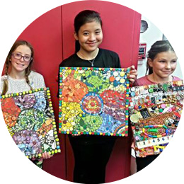 Three girls holding paintings