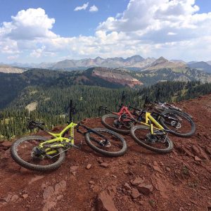 Three mountain bikes laying on the ridge of a trail with a view