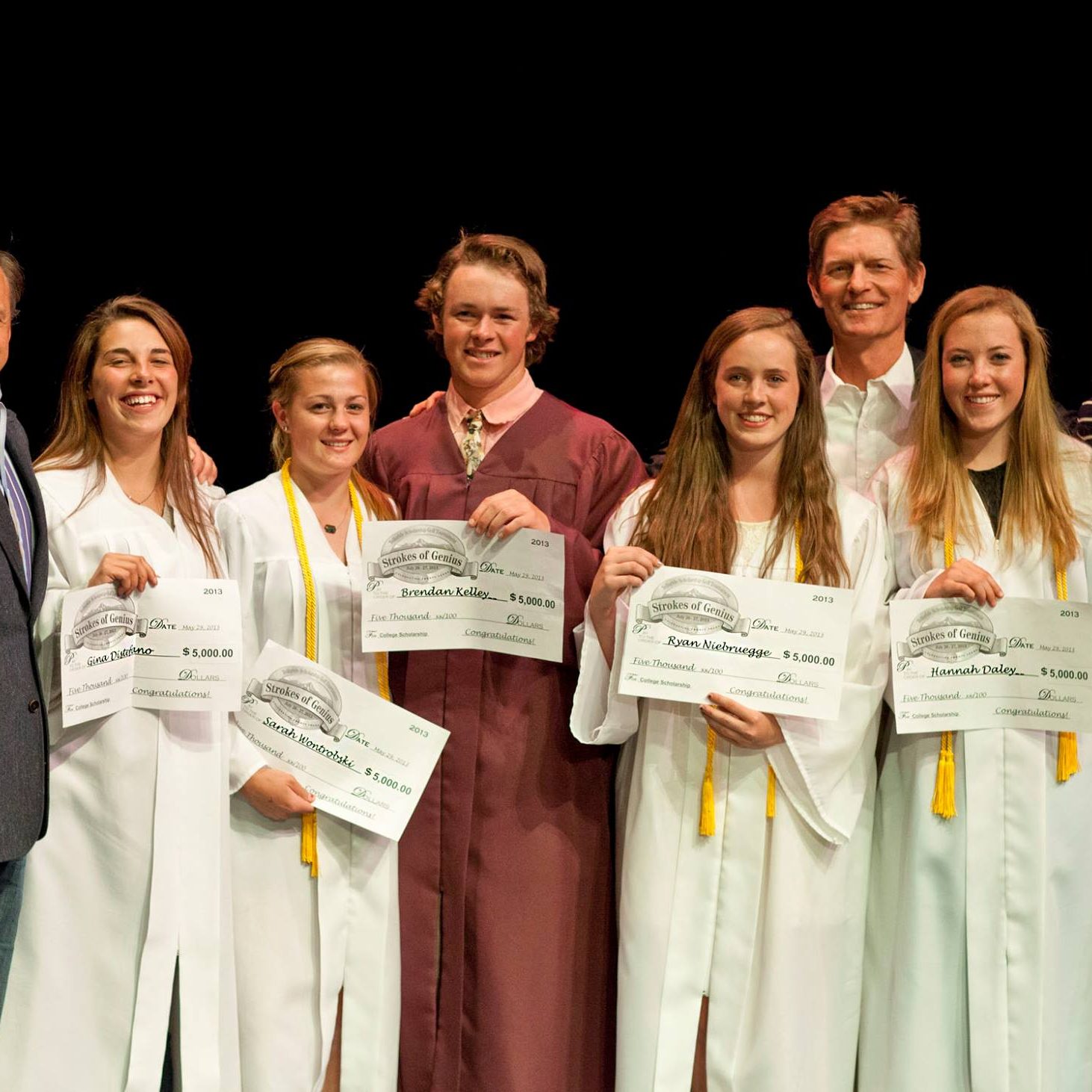 A group of high school graduted holding their diplomas with their teachers